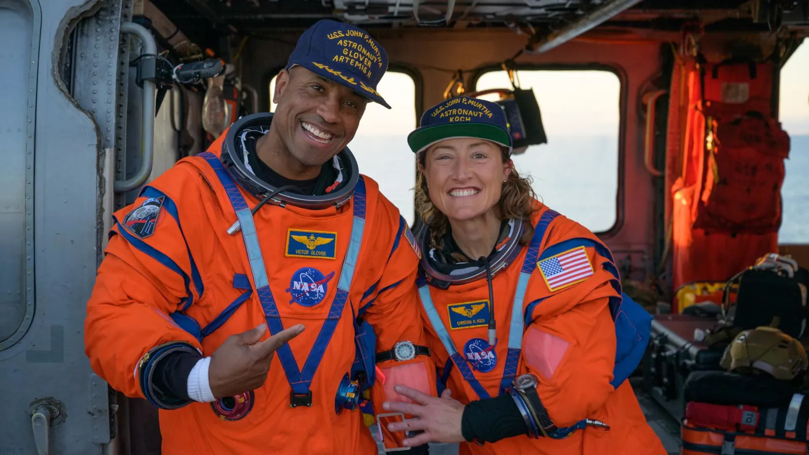 NASA astronauts Victor Glover and Christina Koch wearing the Artemis II watch (Omega X-33 Gen 2) over their flight suits while sitting in a Navy MH-60 Seahawk helicopter on the USS John P. Murtha after splashdown.